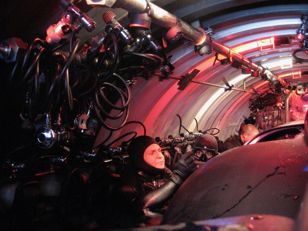 Divers on red-lit submarine interior set, Hawaii