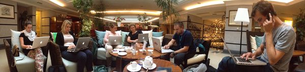 Panoramic view of production crew working on laptops in hotel lobby, Prague