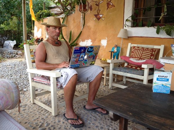 Working on a sticker-covered laptop on a courtyard patio, Ibiza