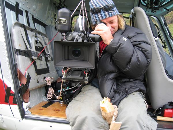 Camera operator with aerial rig inside helicopter, New Zealand