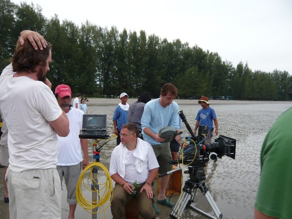 Crew filming on a tidal mudflat with camera and monitor, Thailand