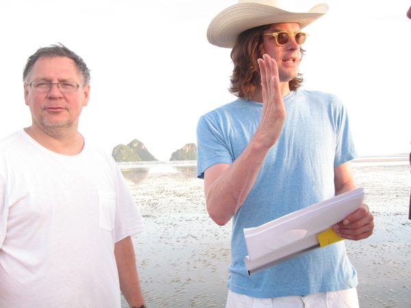 Two crew members with a script on a beach with limestone karst islands, Thailand