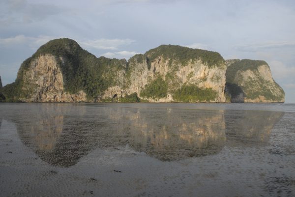 Limestone karst islands reflected in still tidal water, Thailand