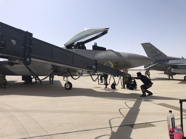 Camera crew operating a remote crane rig beneath a fighter jet, U.S. Air Force