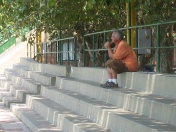 Crew member seated alone on stadium bleachers, Argentina